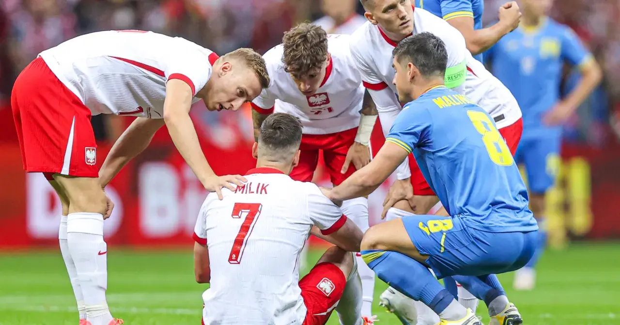 Piłkarze otaczają kolegę z drużyny, który doznał kontuzji. Widoczna jest koszulka z napisem "MILIK" i numerem 7.
