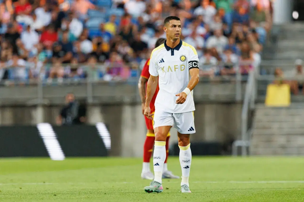 Piłkarz Cristiano Ronaldo na boisku, w białej koszulce z żółtymi detalami. Ile goli strzelił Ronaldo? To pytanie nurtuje fanów.