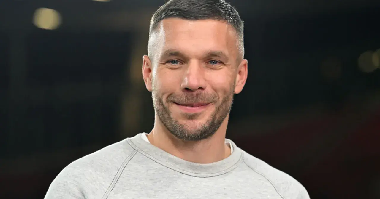 Uśmiechnięty Łukasz Podolski w szarej bluzie. Jego kariera piłkarska i biznesy budują imponujący lukas podolski majątek.