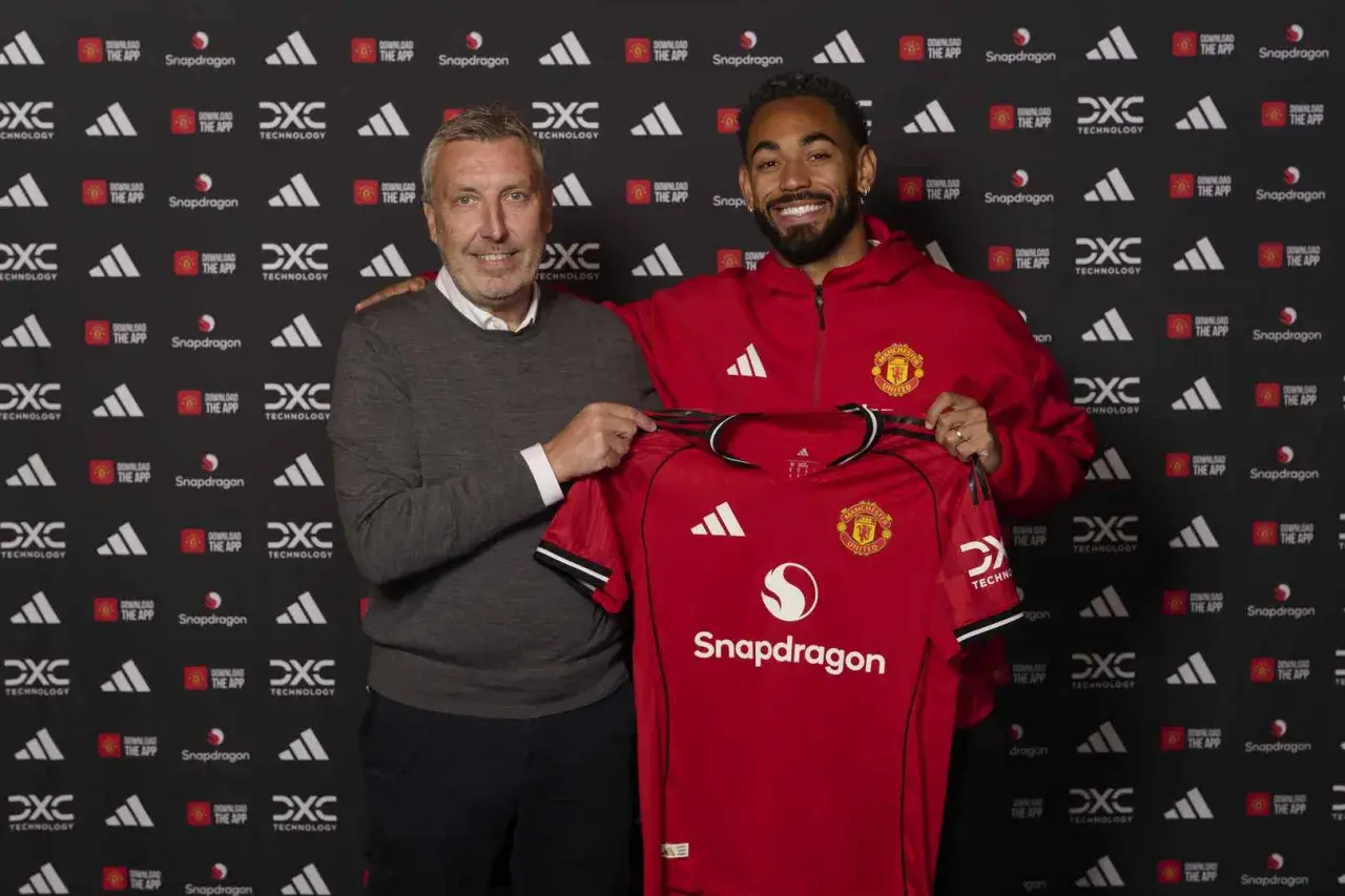Dwóch mężczyzn prezentuje czerwoną koszulkę Manchester United. To ważny moment w kontekście manchester united transfery.