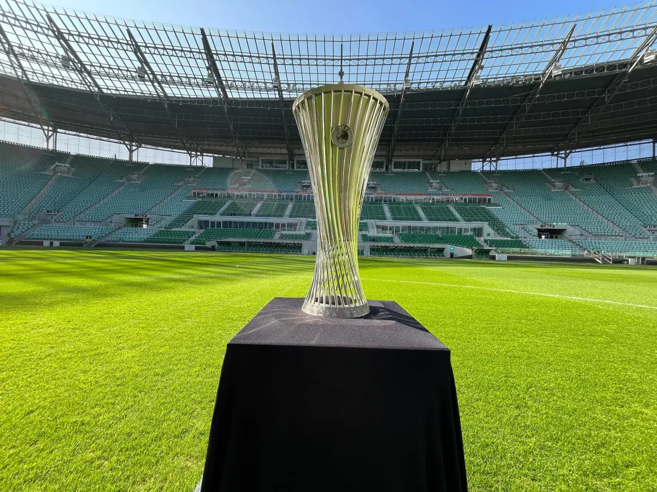 Błyszczący puchar Konfederacji UEFA na tle pustego stadionu.