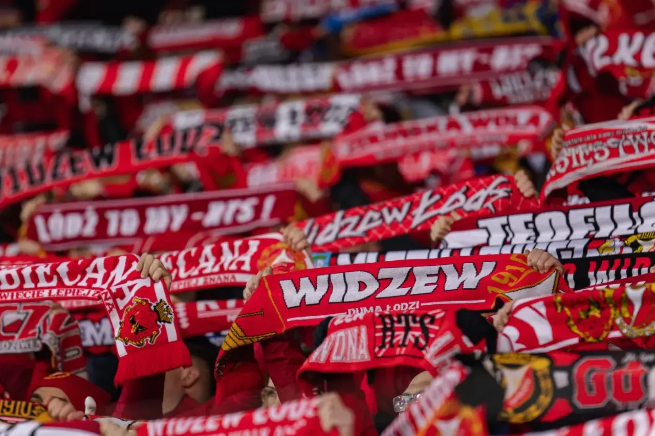 Tłum kibiców Widzewa Łódź z szalikami. Fani świętują, a na szalikach widnieją napisy "Widzew", "Łódź to my" i rok 1910. To symbol ich dumy i wsparcia dla klubu, który zawsze budzi emocje, zwłaszcza podczas ważnych widzew łódź transfery.