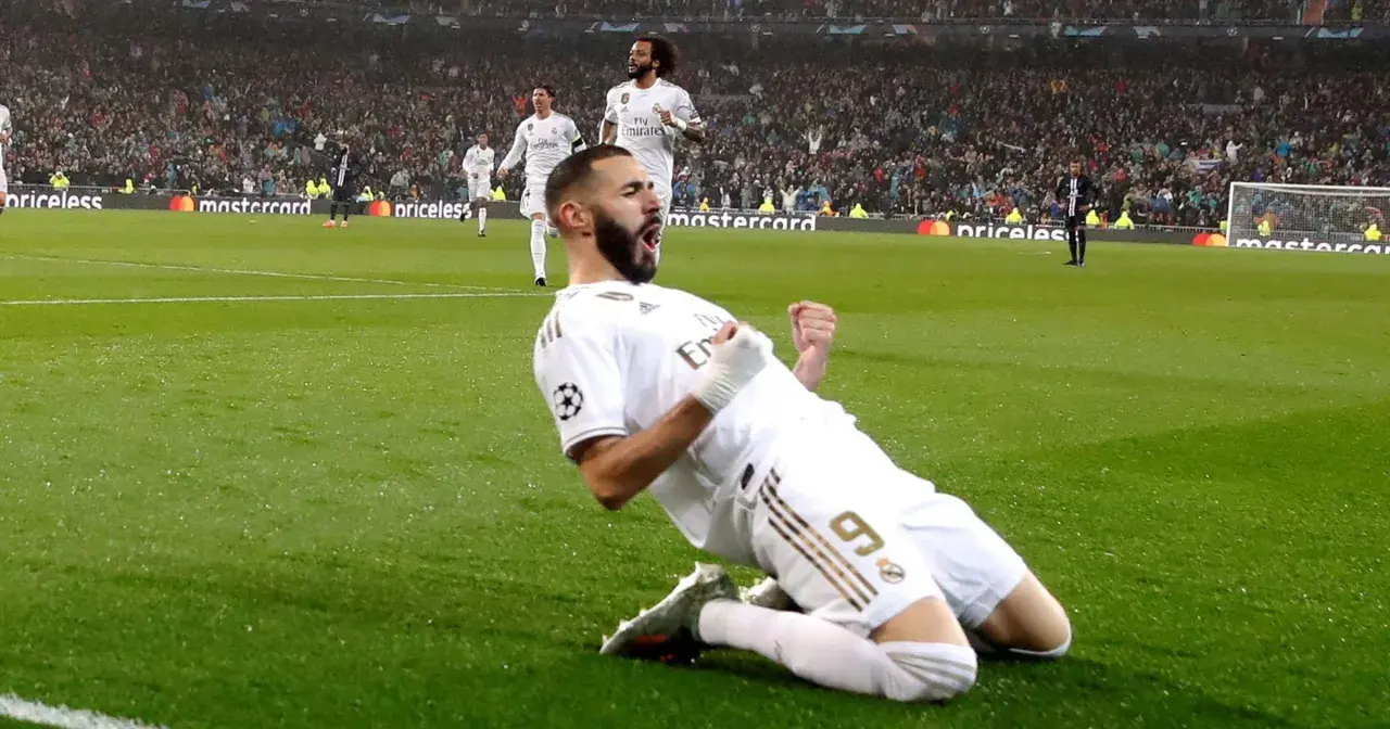 Karim Benzema świętuje zwycięstwo w Lidze Mistrzów, klęcząc na boisku w białej koszulce Realu Madryt.