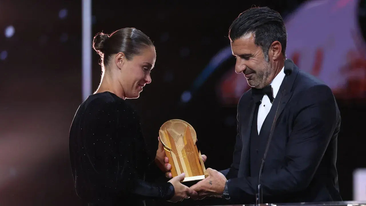 Piłkarz wręcza trofeum złota piłka kobiet.