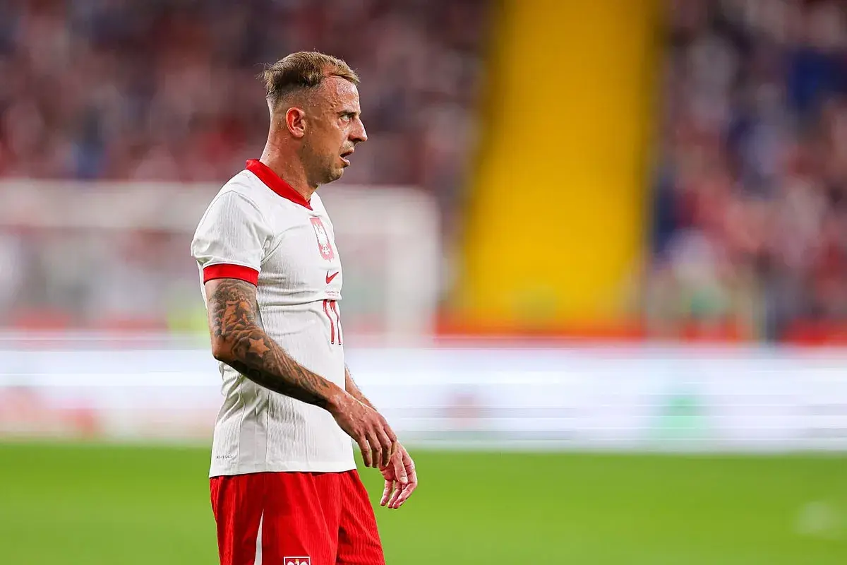 Piłkarz Kamil Grosicki w białej koszulce i czerwonych spodenkach, z tatuażami na ramieniu. Jego majątek budowany latami na boisku.