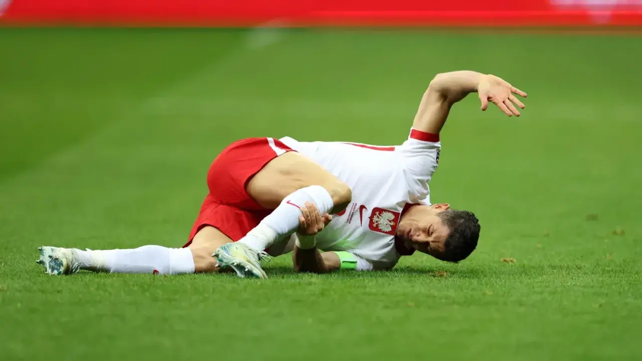 Robert Lewandowski leży na trawie, trzymając się za nogę. Wygląda na to, że to poważna lewandowski kontuzja.