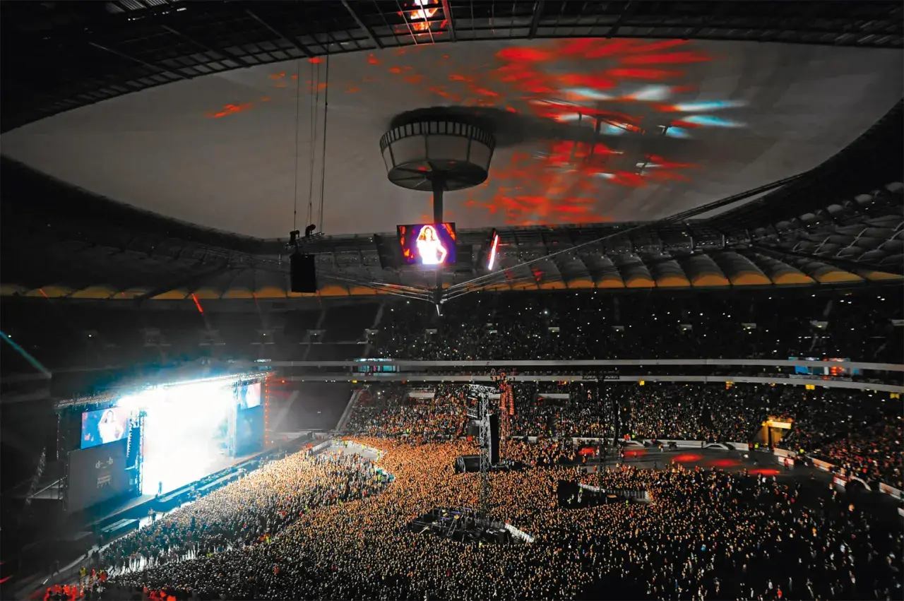 Koncert na Stadionie Narodowym, gdzie jego ogromna pojemność pozwala pomieścić tłumy fanów. Światła i ekrany tworzą niesamowitą atmosferę.