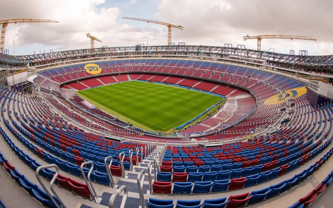 Stadion Camp Nou w trakcie przebudowy, z widocznymi dźwigami i częściowo pustymi trybunami.