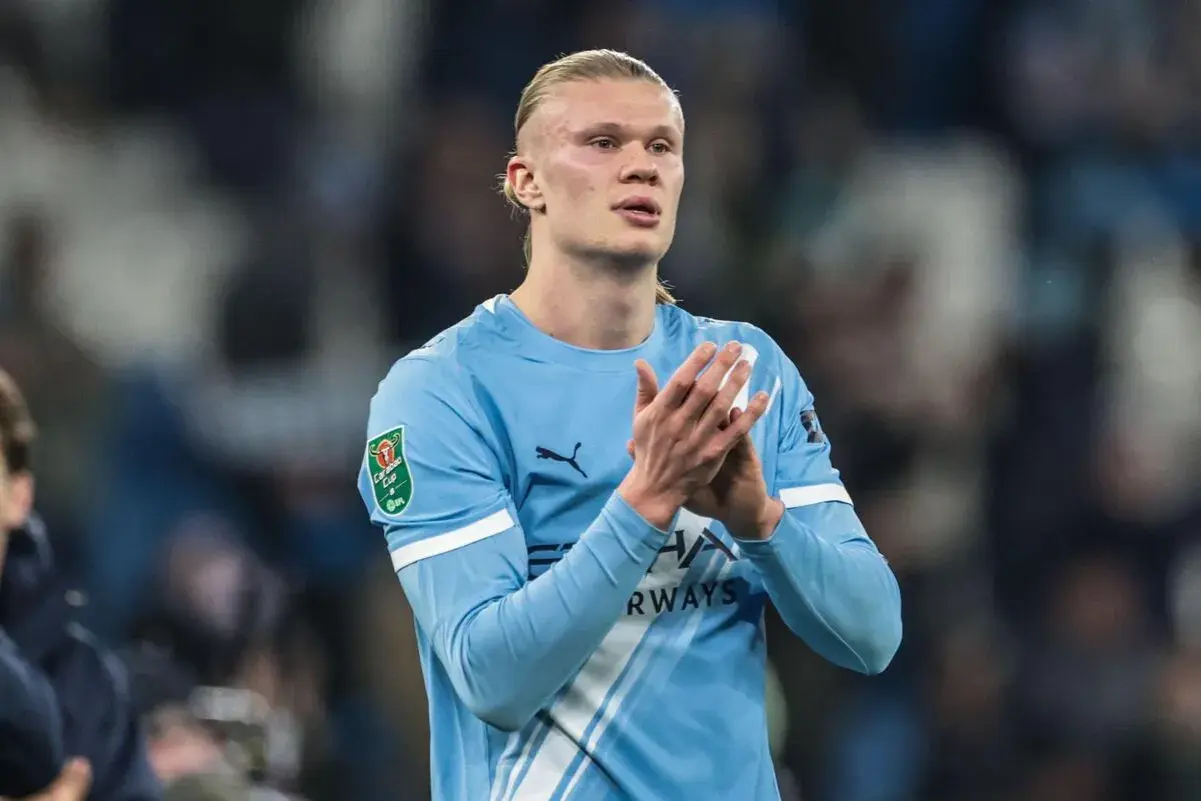 Erling Haaland w błękitnej koszulce Manchesteru City klaszcze, patrząc w bok.