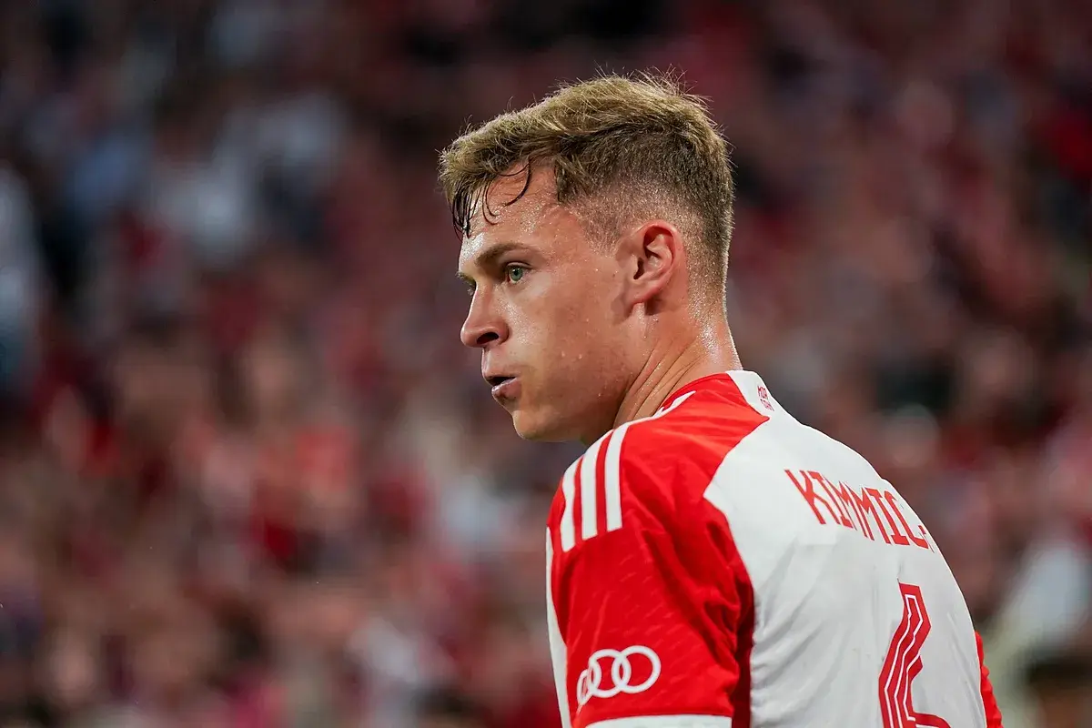 Joshua Kimmich, spocony po meczu, w białej koszulce z czerwonymi pasami i logo Audi.