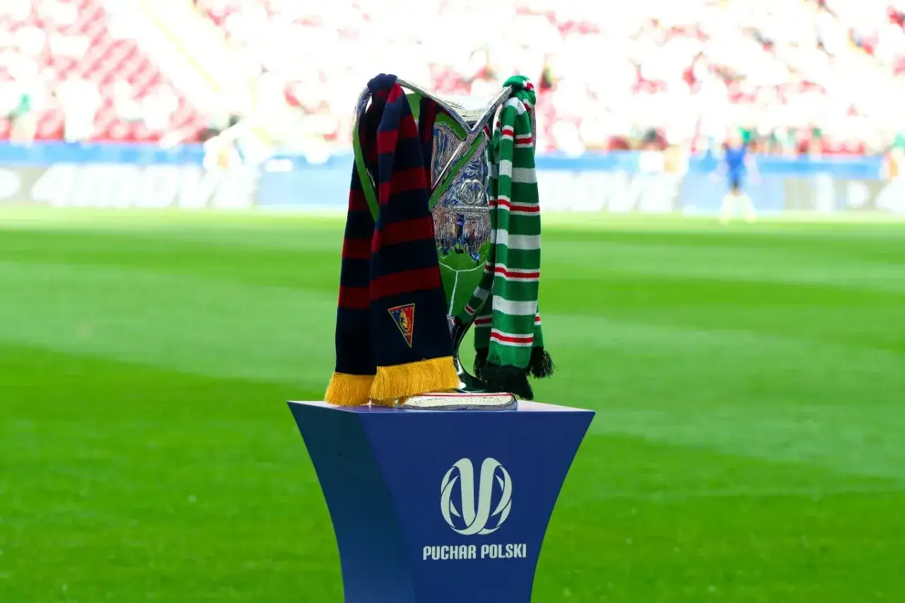 Trofea piłkarskie na tle stadionu. Dwa szaliki, jeden granatowo-bordowy, drugi zielono-biało-czerwony, owinięte wokół pucharu. To symboliczne pary pucharu polski.