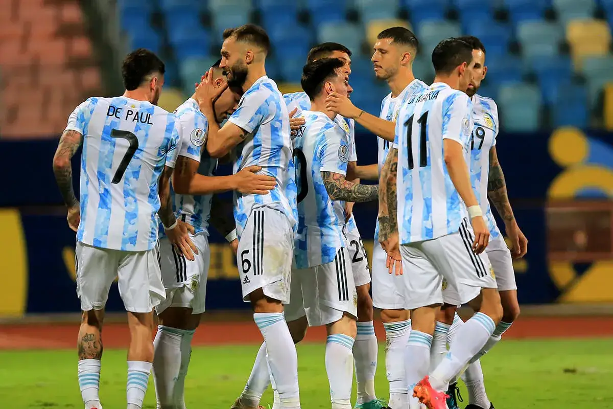 Piłkarze reprezentacji Argentyny w białych i błękitnych koszulkach świętują razem na boisku.