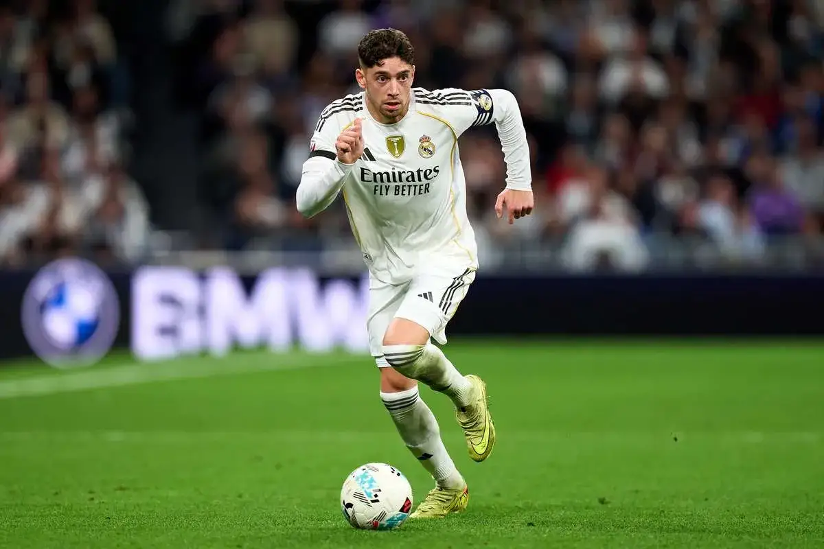 Federico Valverde w białej koszulce Realu Madryt drybluje z piłką na zielonej murawie, gotowy do kolejnego zagrania.