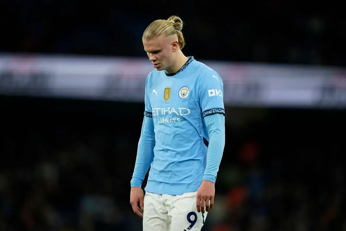 Erling Haaland w błękitnej koszulce Manchesteru City, z charakterystycznym kucykiem, spogląda w dół, być może po nieudanej akcji.