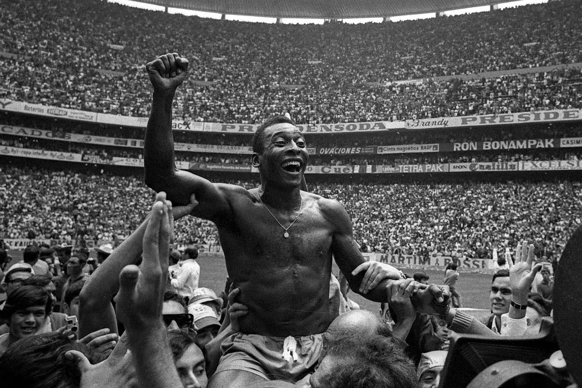 Pele w swoim najlepszym wieku, niesiony na rękach przez tłum kibiców na stadionie, świętuje zwycięstwo.