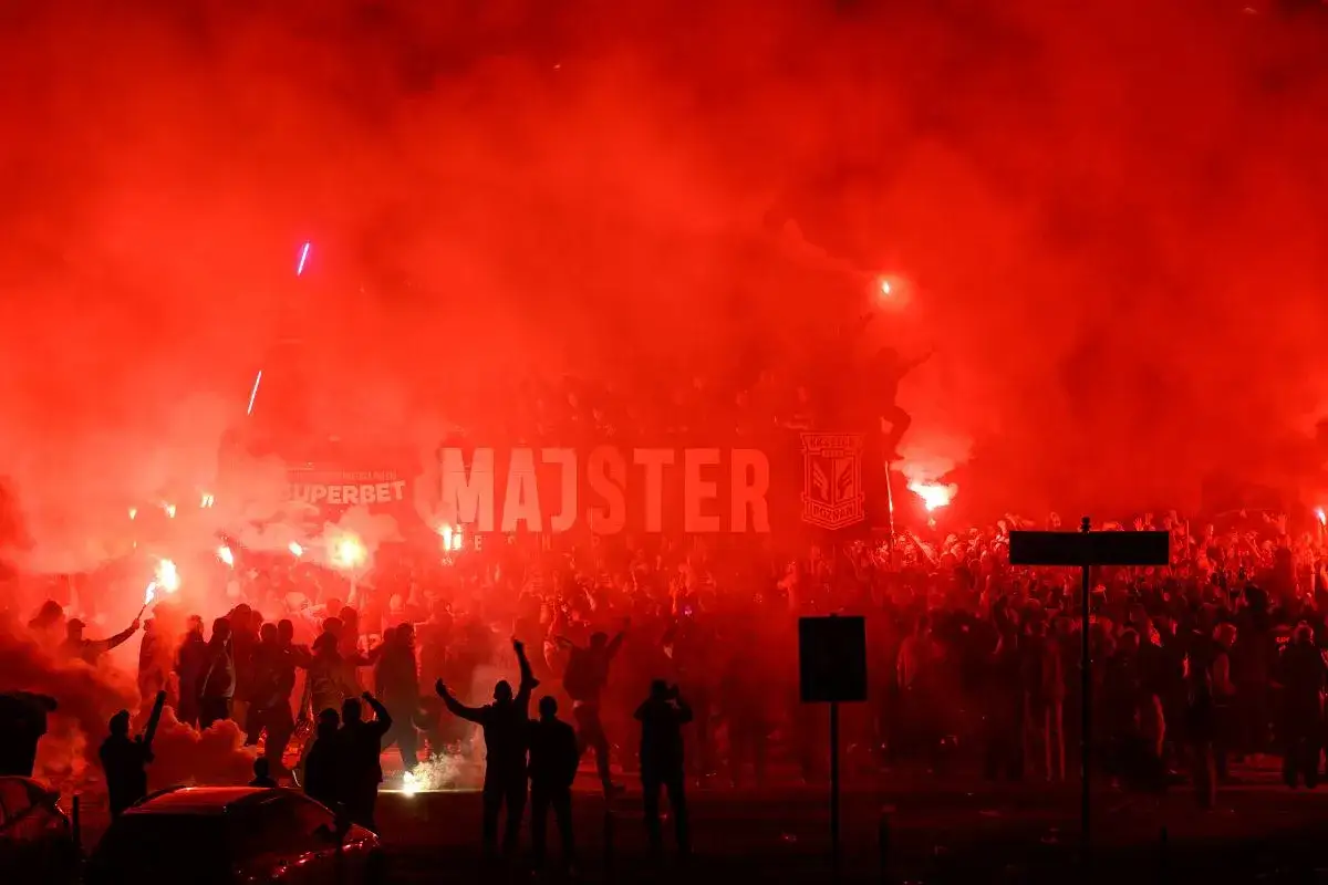 Tłum świętuje, odpalając race. Na banerze widnieje napis 