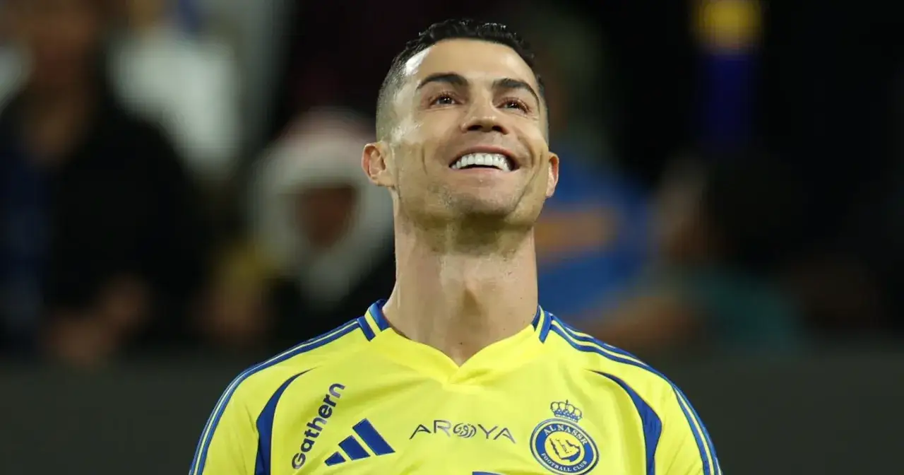 Uśmiechnięty Cristiano Ronaldo w żółtej koszulce swojego klubu Al Nassr.