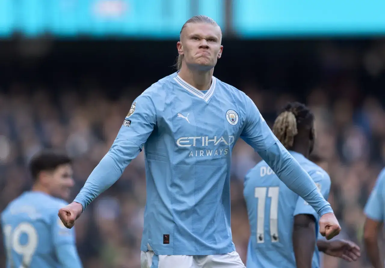 Erling Haaland, najdroższy piłkarz świata, w błękitnej koszulce Manchesteru City, z zaciętą miną i zaciśniętą pięścią.