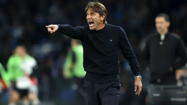 Antonio Conte, znany z taktyki catenaccio, krzyczy i wskazuje palcem, instruując zawodników na boisku.